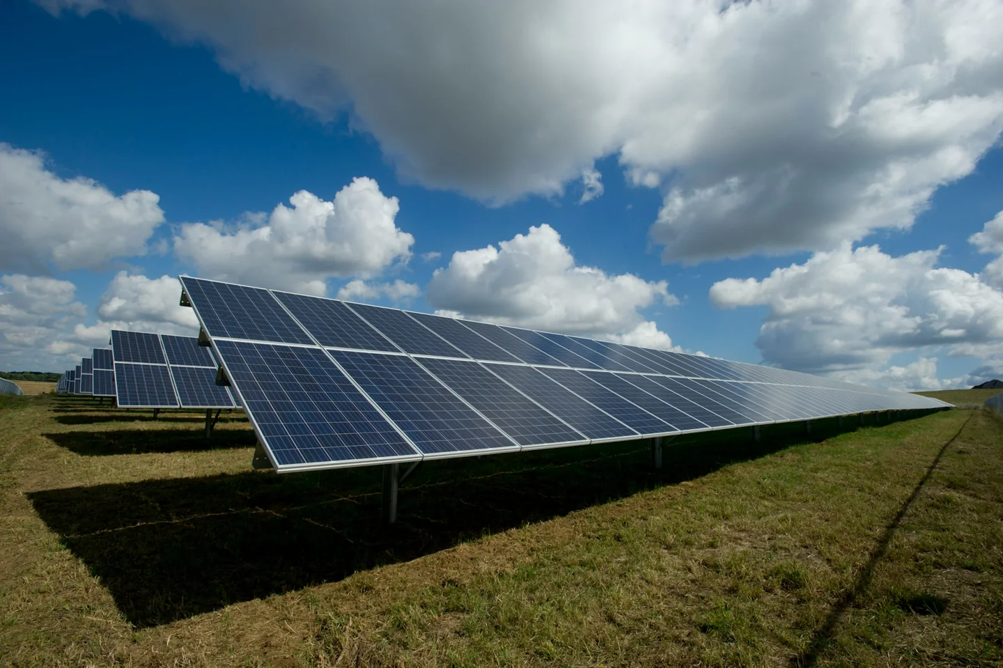 Solar panels in an open landscape beneath a cloud-filled sky
